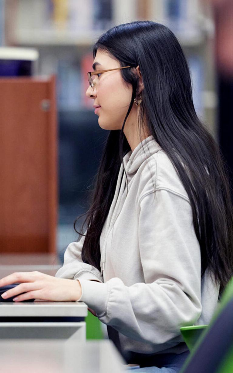 Photo of a student on a computer in the library